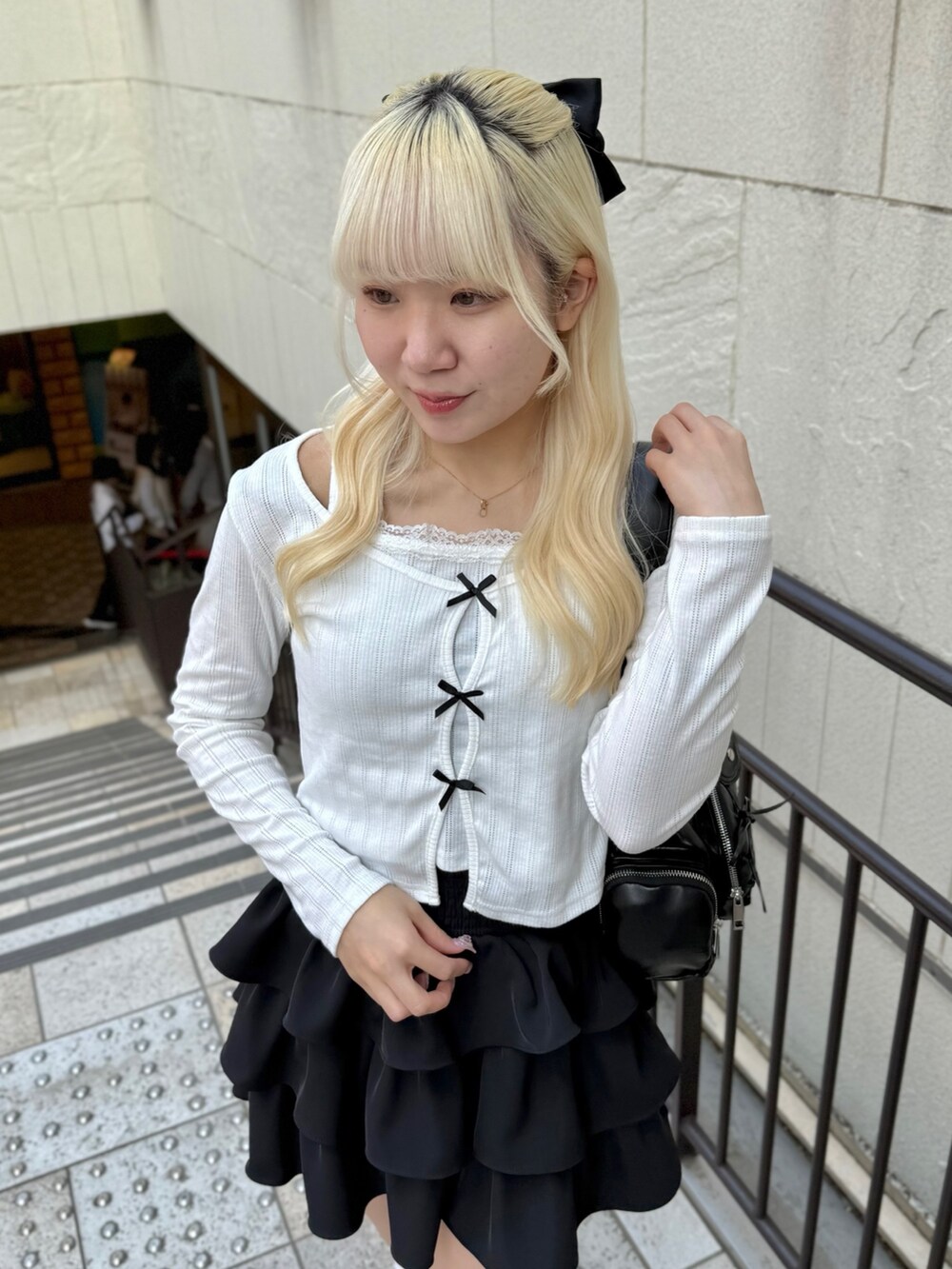 ブラック系のスカート、ホワイト系のTシャツ/カットソー、ブラック系のショルダーバッグを着用したレディースの春コーディネートの3枚目の写真