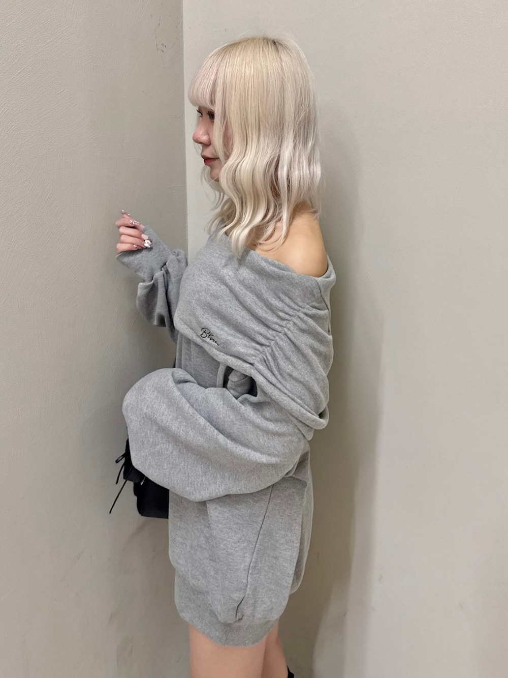 グレー系のパーカー、ブラック系のショルダーバッグ、ブラック系のスニーカーを着用したレディースの春コーディネートの5枚目の写真