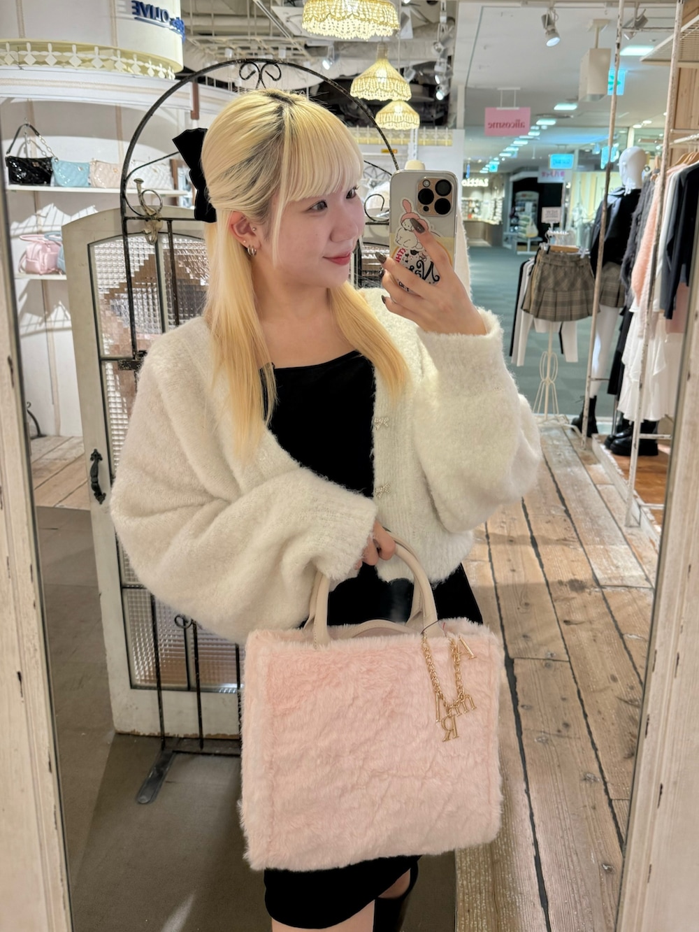 ピンク系のトートバッグ、ブラック系のブーツ、ホワイト系のカーディガン/ボレロを着用したレディースの秋コーディネートの2枚目の写真