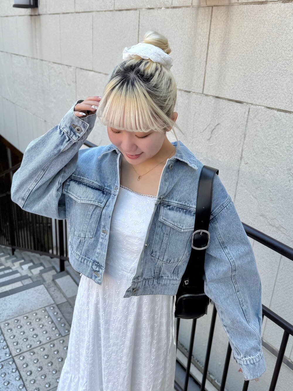 ブルー系のデニムジャケット、ブラック系のショルダーバッグ、ホワイト系のワンピースを着用したレディースの春コーディネートの3枚目の写真