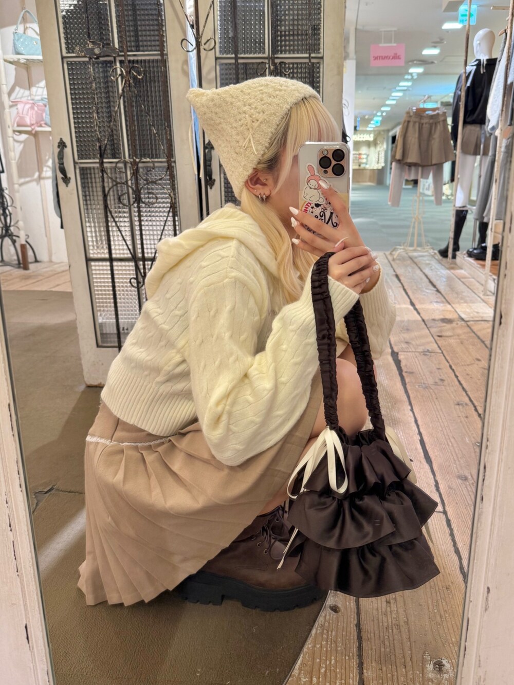 ベージュ系のスカート、ホワイト系のパーカー、ブラウン系のブーツを着用したレディースの秋コーディネートの3枚目の写真