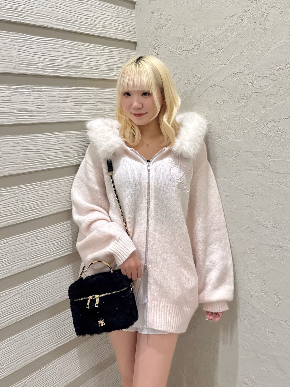ピンク系のニット/セーター、ブラック系のショルダーバッグ、ホワイト系のブーツを着用したレディースの夏コーディネートの5枚目の写真