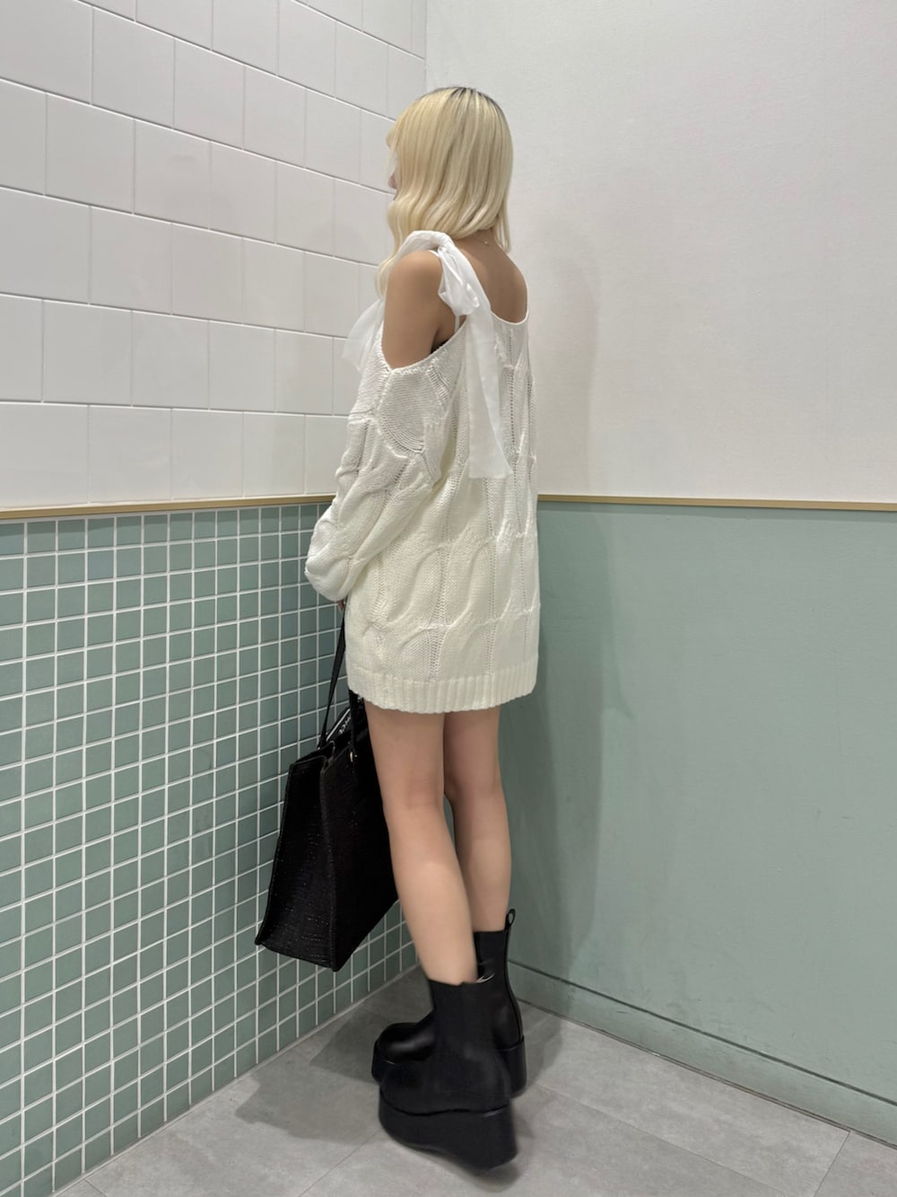 ブラック系のトートバッグ、ブラック系のブーツ、ホワイト系のワンピースを着用したレディースの冬コーディネートの2枚目の写真