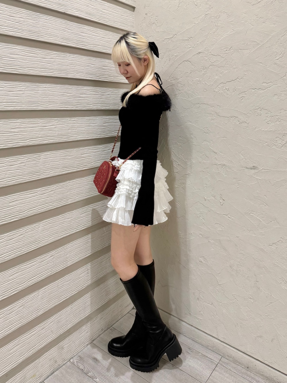 ブラック系のニット/セーター、ホワイト系のスカート、ブラック系のブーツを着用したレディースの秋コーディネートの2枚目の写真