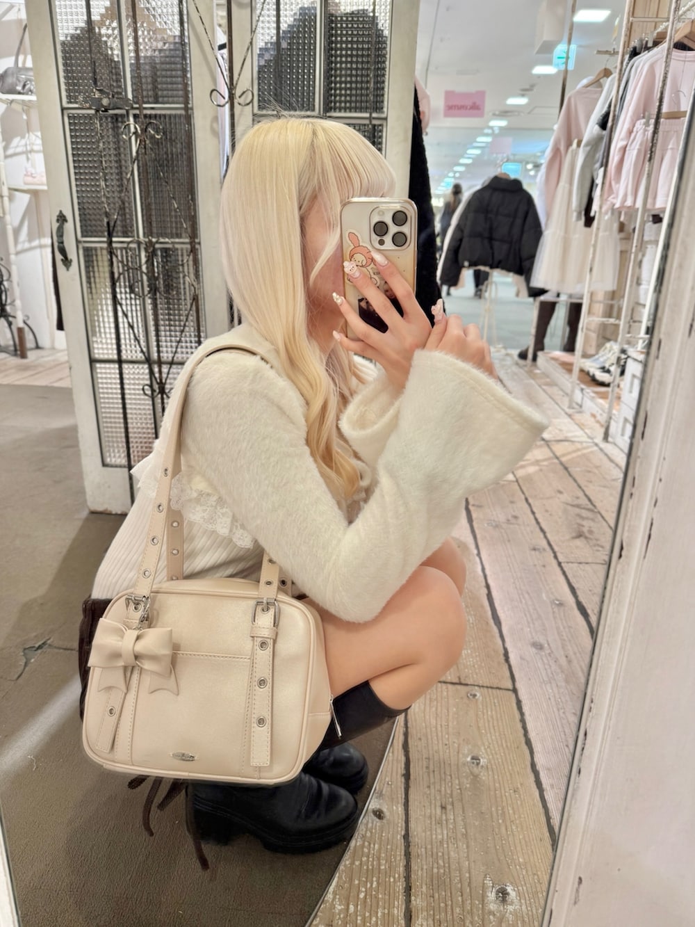 ホワイト系のアンサンブル、ホワイト系のショルダーバッグ、ブラウン系のスカートを着用したレディースの冬コーディネートの3枚目の写真