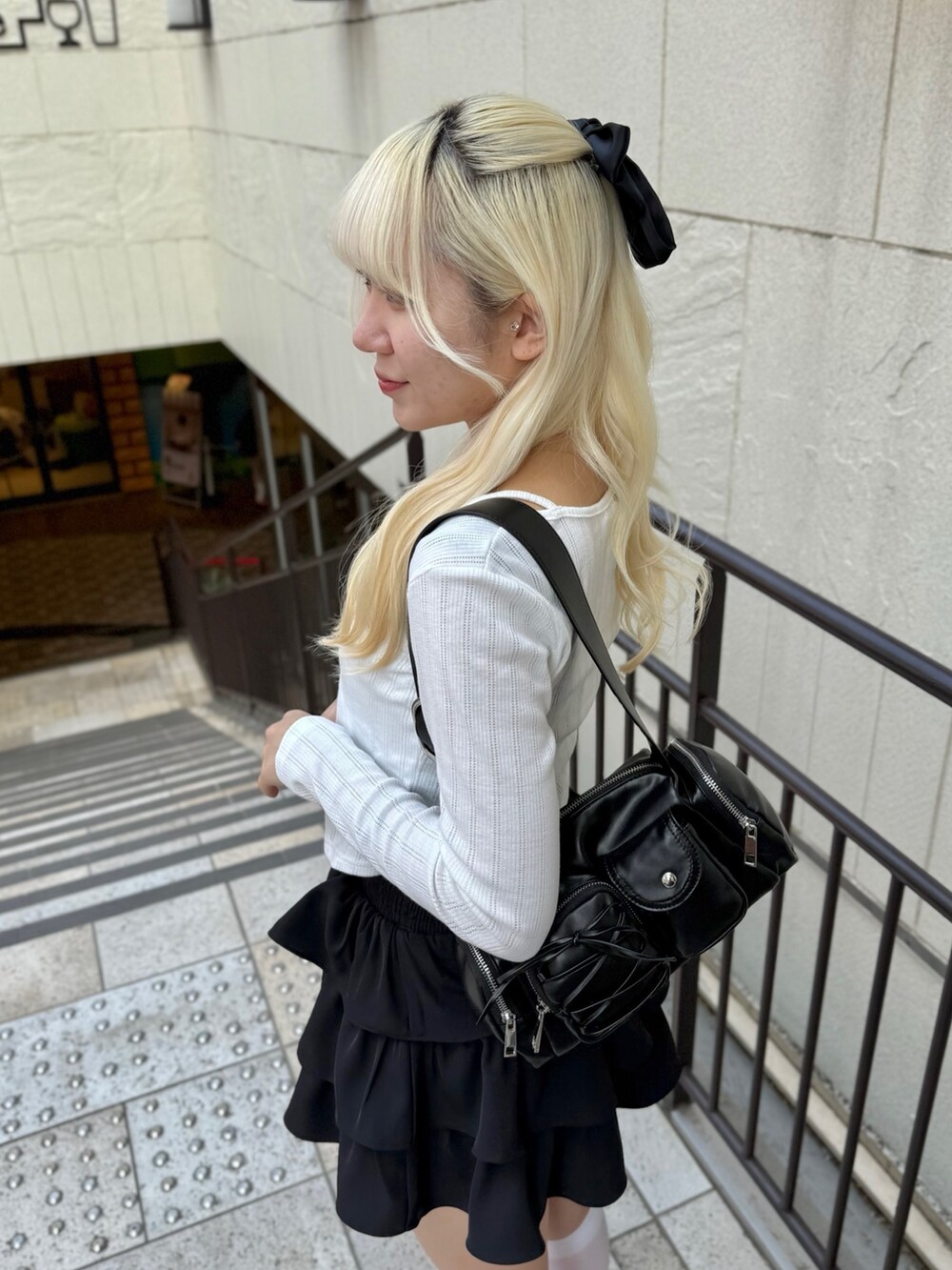 ブラック系のスカート、ホワイト系のTシャツ/カットソー、ブラック系のショルダーバッグを着用したレディースの春コーディネートの4枚目の写真