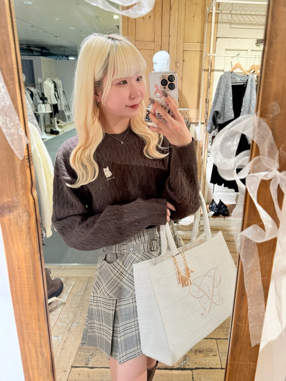 ブラウン系のブーツ、ホワイト系のトートバッグ、その他のスカートを着用したレディースの秋コーディネートの2枚目の写真