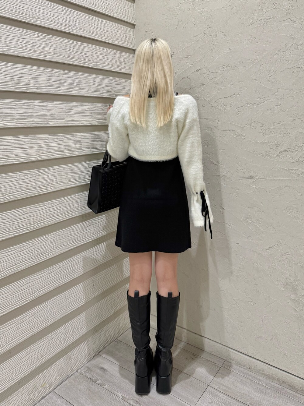 ブラック系のトートバッグ、ブラック系のワンピース、ブラック系のブーツを着用したレディースの秋コーディネートの3枚目の写真