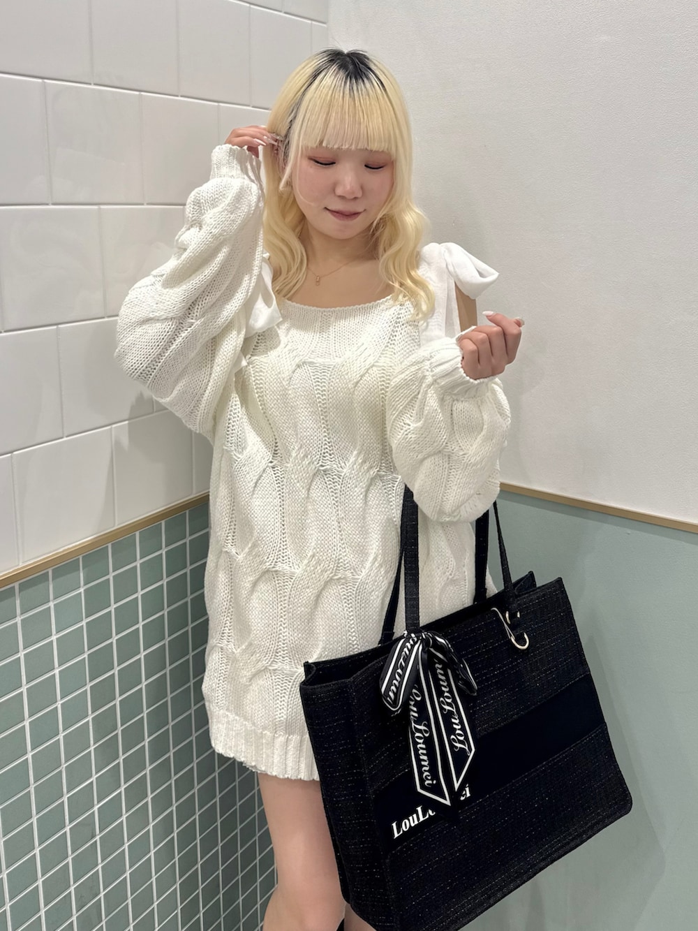 ブラック系のトートバッグ、ブラック系のブーツ、ホワイト系のワンピースを着用したレディースの冬コーディネートの5枚目の写真