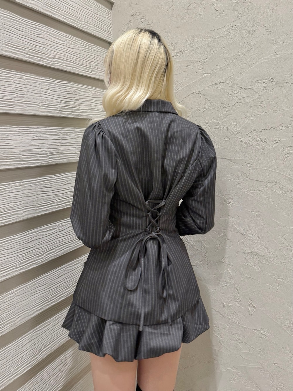 グレー系のテーラードジャケット、グレー系のスカート、ブラック系のショルダーバッグを着用したレディースの冬コーディネートの6枚目の写真