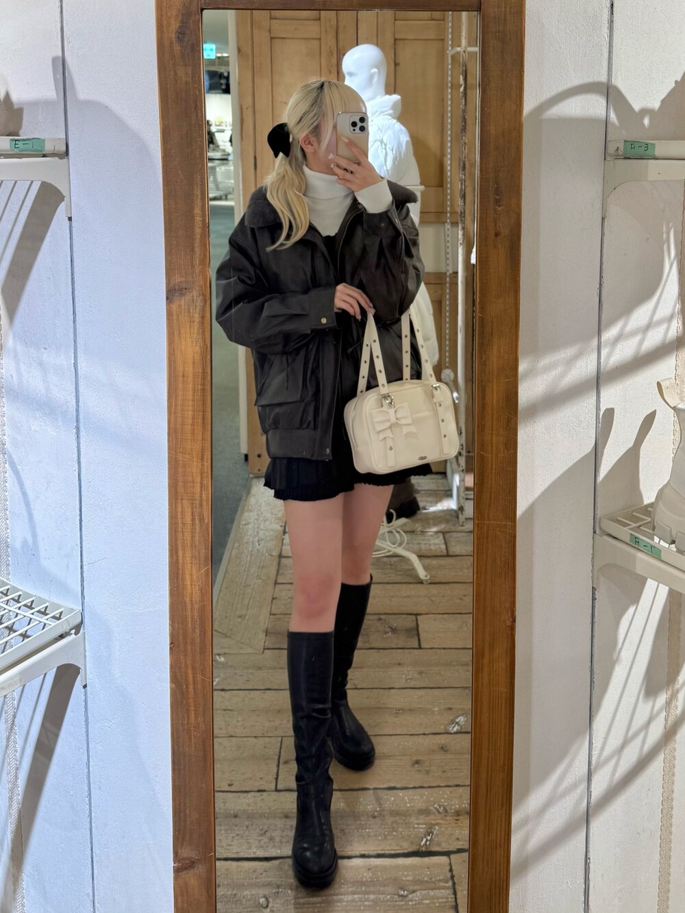 ブラウン系のブルゾン、ブラック系のワンピース、ホワイト系のニット/セーターを着用したレディースの冬コーディネートの2枚目の写真