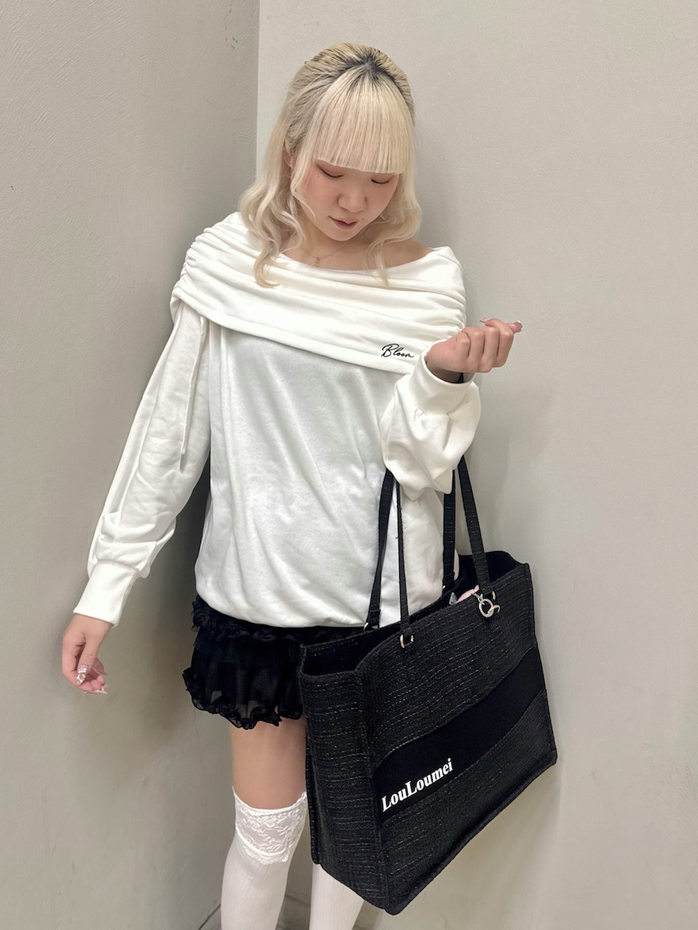 ホワイト系のパーカー、ブラック系のトートバッグ、ブラック系のスカートを着用したレディースの春コーディネートの4枚目の写真