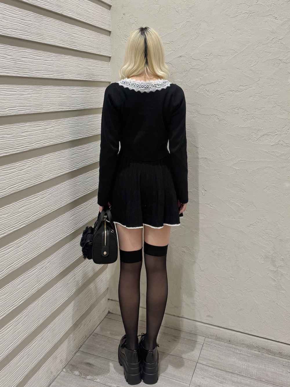 ブラック系のセットアップ、ブラック系のショルダーバッグ、ブラック系のローファーを着用したレディースの冬コーディネートの3枚目の写真