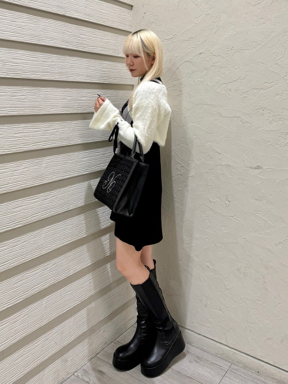 ブラック系のトートバッグ、ブラック系のワンピース、ブラック系のブーツを着用したレディースの秋コーディネートの2枚目の写真