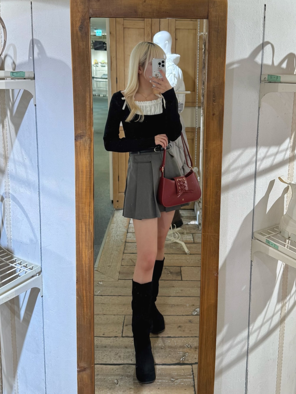 ブラック系のニット/セーター、レッド系のショルダーバッグ、グレー系のスカートを着用したレディースの冬コーディネートの2枚目の写真