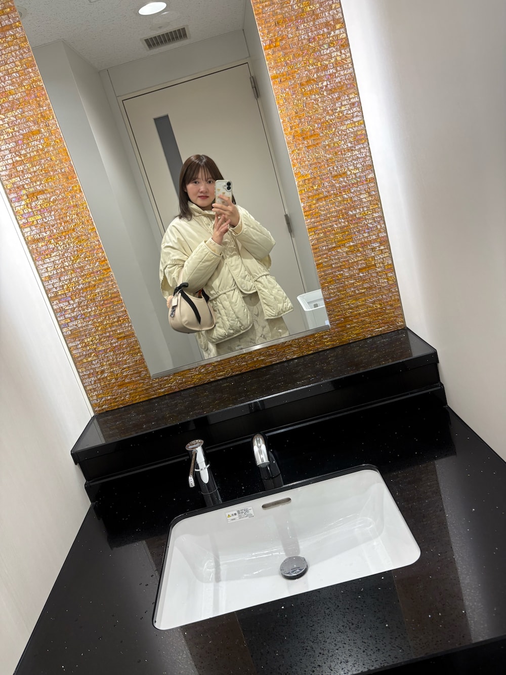 ブラック系のブーツ、ホワイト系のブルゾン、ホワイト系のワンピース/ドレスを着用したレディースの冬コーディネートの2枚目の写真