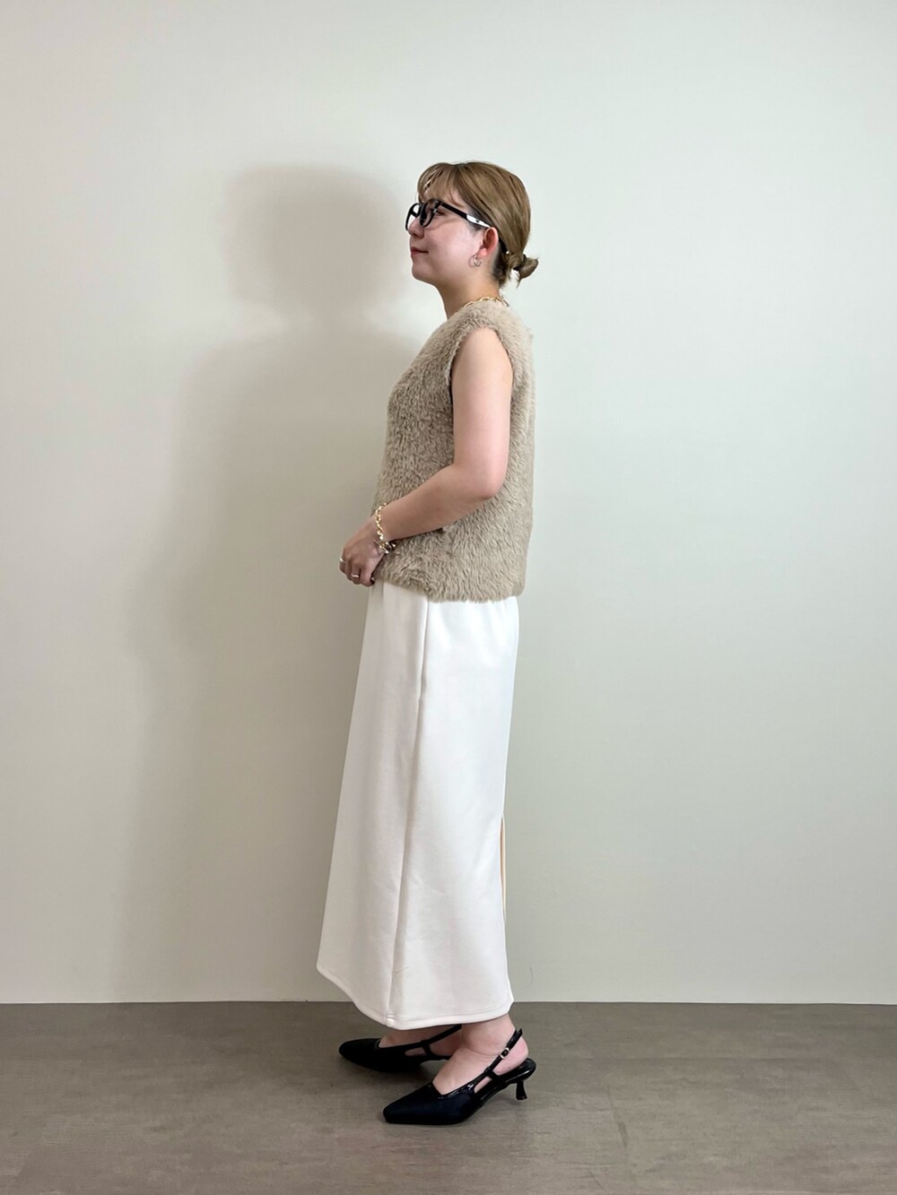 ホワイト系のスカート、ベージュ系のニット/セーター、ブラック系のトートバッグを着用したレディースの夏コーディネートの2枚目の写真