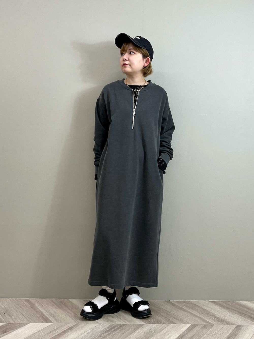 グレー系のワンピース、ブラック系のTシャツ/カットソー、ゴールド系のネックレスを着用したレディースの春コーディネートの3枚目の写真