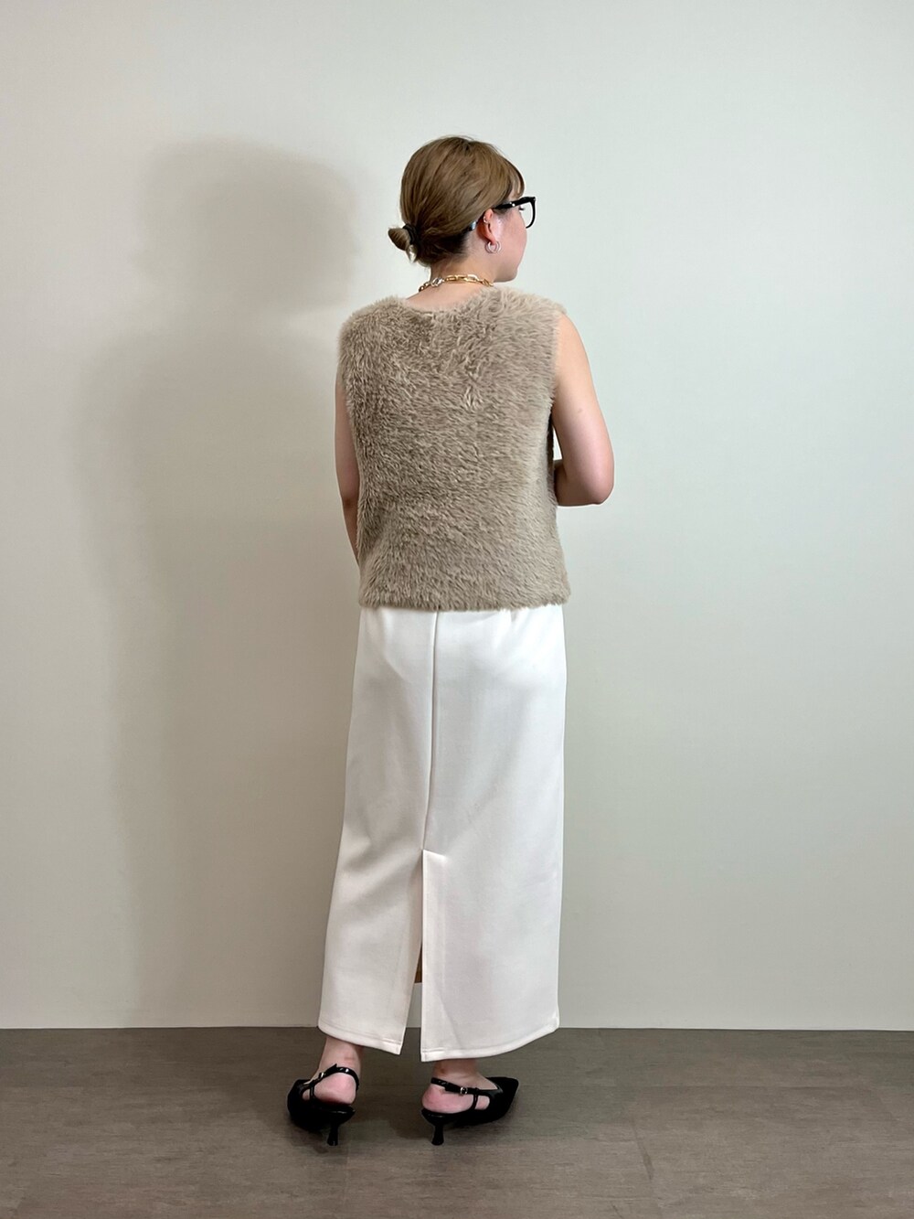 ホワイト系のスカート、ベージュ系のニット/セーター、ブラック系のトートバッグを着用したレディースの夏コーディネートの3枚目の写真