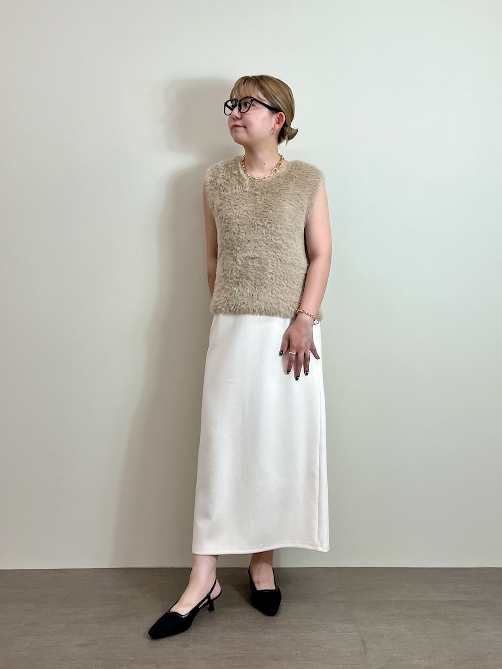 ホワイト系のスカート、ベージュ系のニット/セーター、ブラック系のトートバッグを着用したレディースの夏コーディネートの4枚目の写真