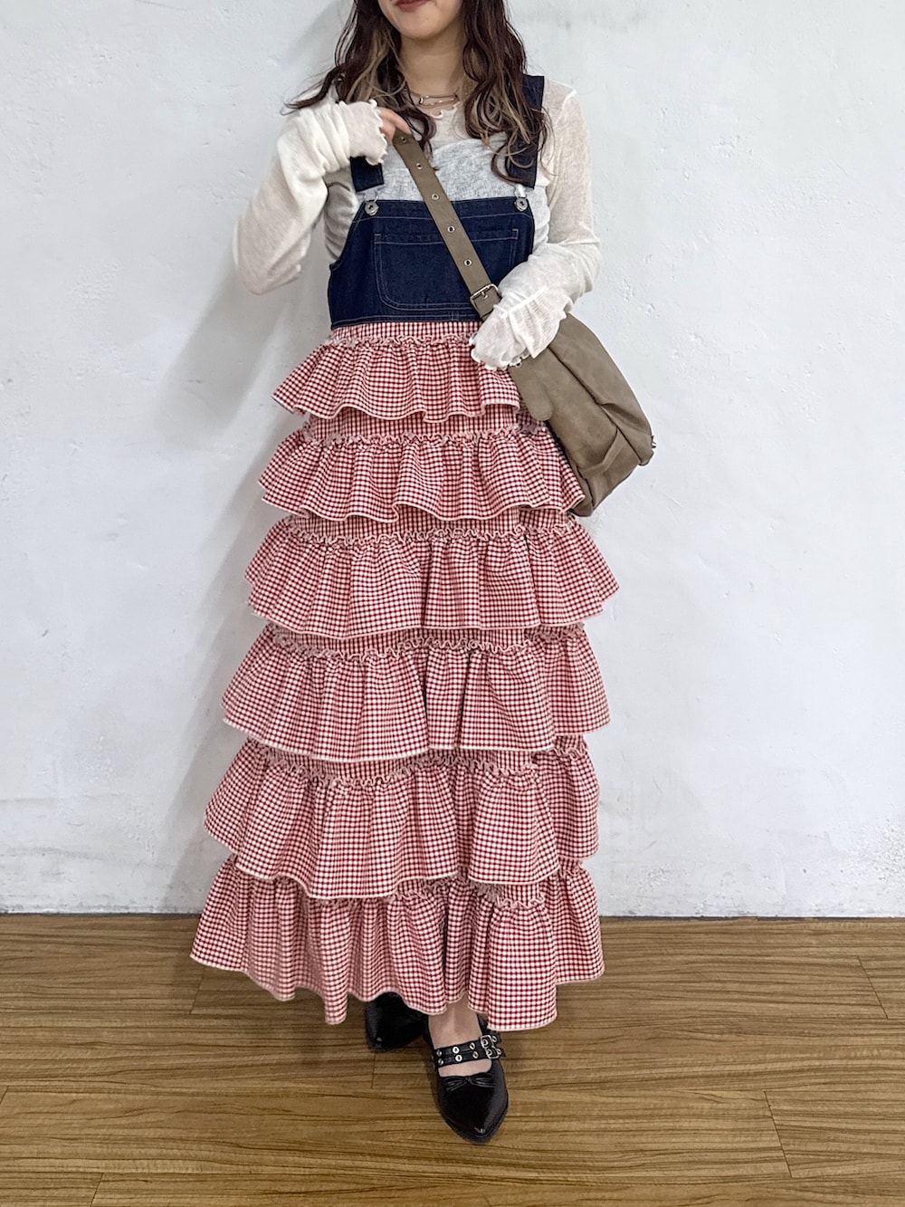 レッド系のジャンパースカート、ホワイト系のTシャツ/カットソー、ブラック系のキャップを着用したレディースの春コーディネートの3枚目の写真