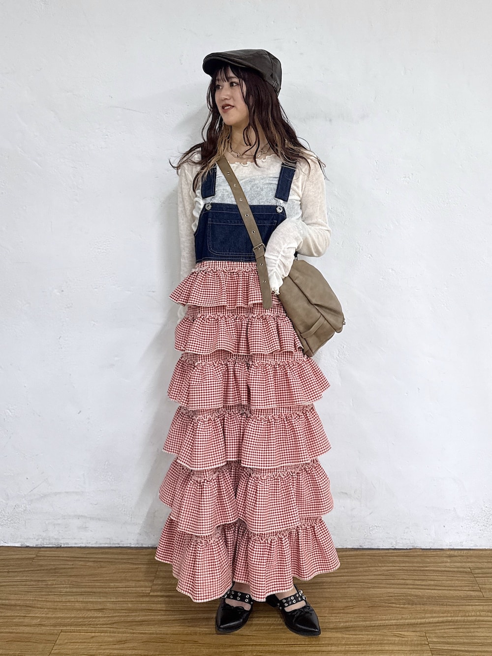 レッド系のジャンパースカート、ホワイト系のTシャツ/カットソー、ブラック系のキャップを着用したレディースの春コーディネートの2枚目の写真