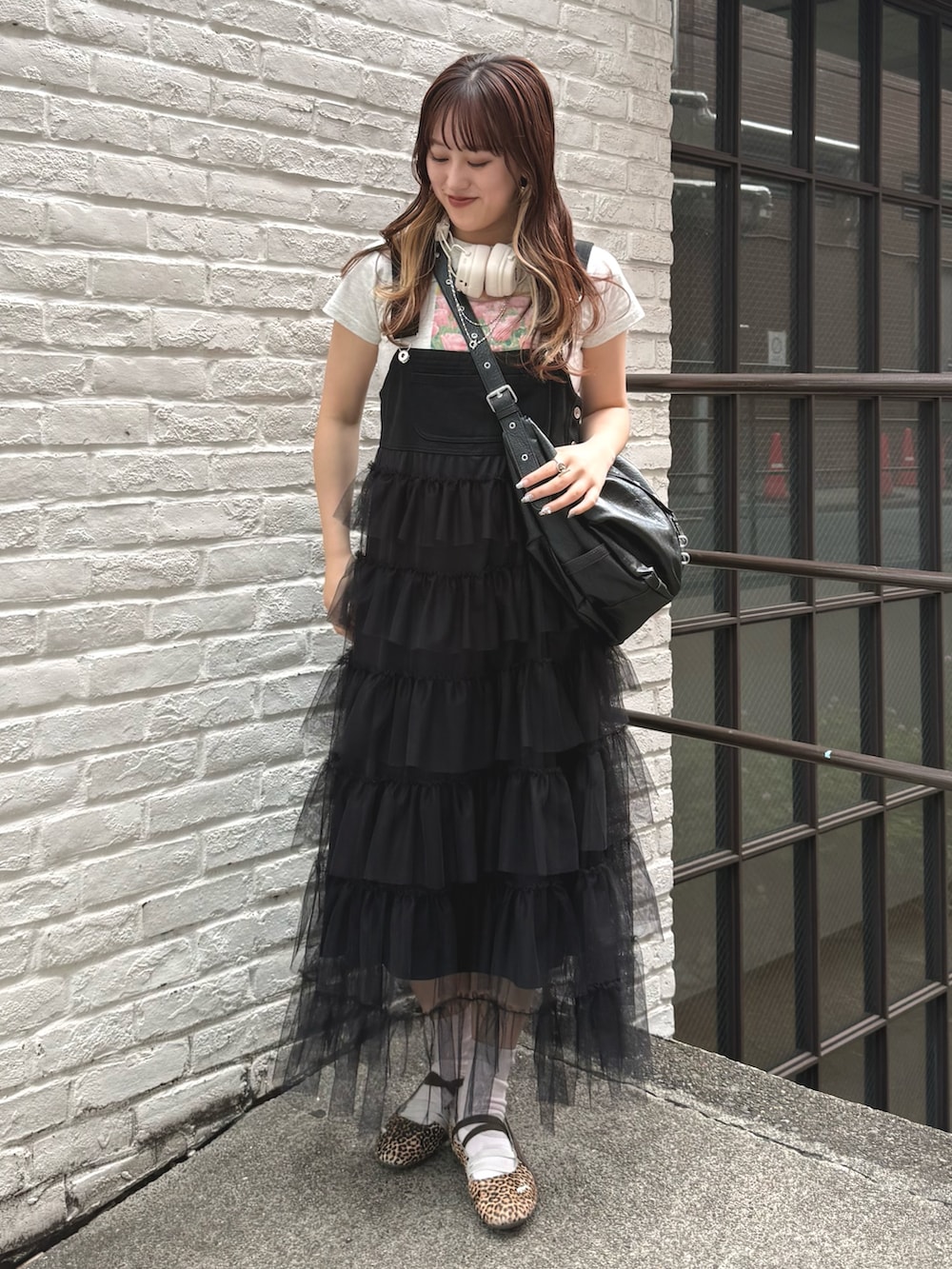 ブラック系のジャンパースカート、ブラック系のトートバッグ、ホワイト系のTシャツ/カットソーを着用したレディースの春コーディネートの3枚目の写真