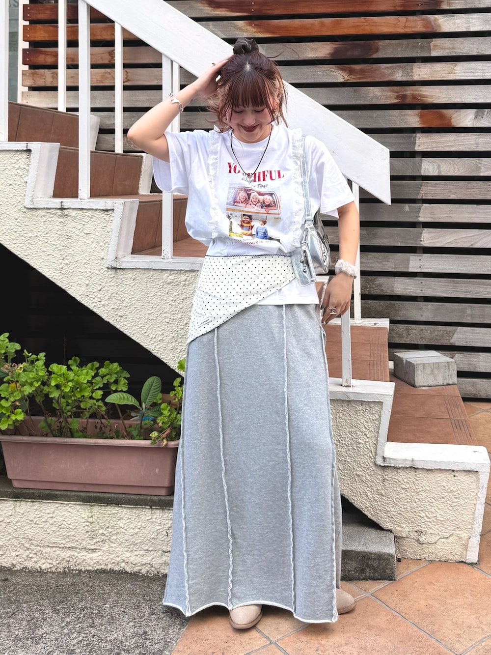 グレー系のスカート、ホワイト系のTシャツ/カットソー、シルバー系のトートバッグを着用したレディースの春コーディネートの2枚目の写真