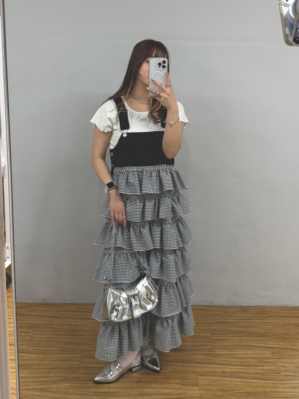 シルバー系のトートバッグ、ブラック系のジャンパースカートを着用したレディースの春コーディネートの2枚目の写真