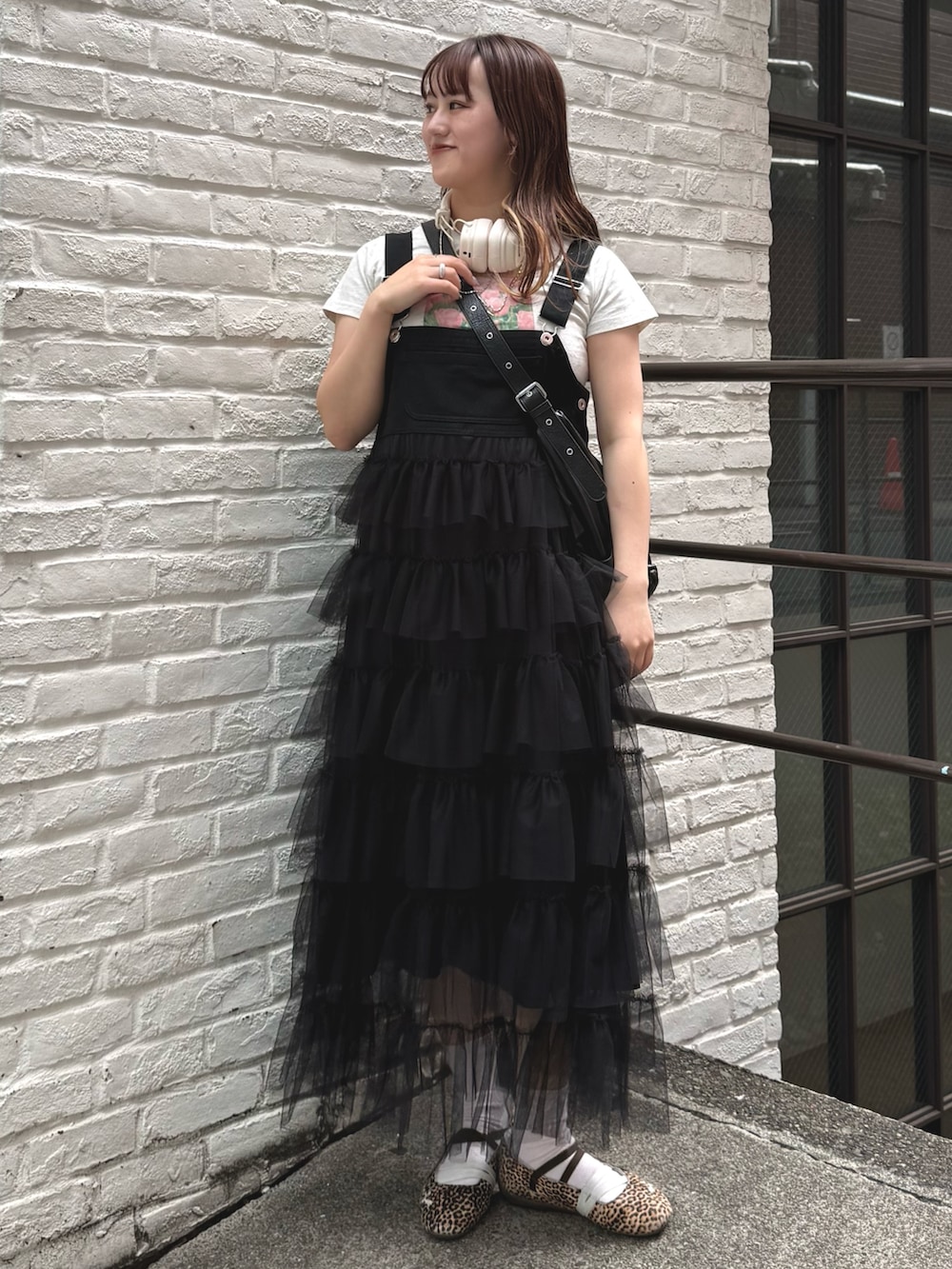 ブラック系のジャンパースカート、ブラック系のトートバッグ、ホワイト系のTシャツ/カットソーを着用したレディースの春コーディネートの2枚目の写真