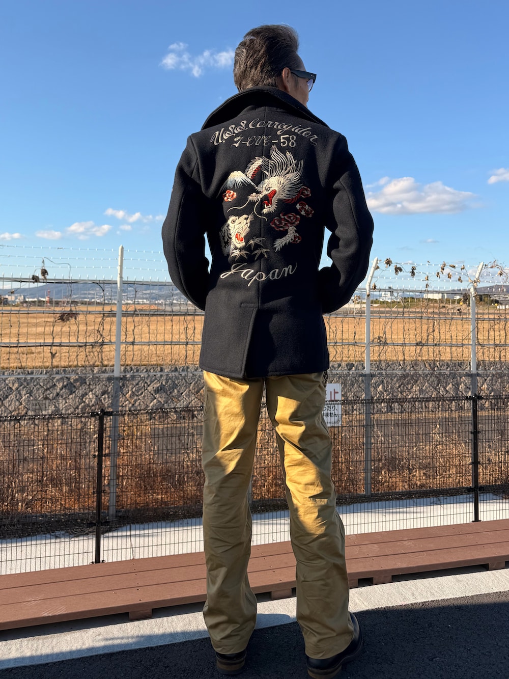 ブラック系のブーツ、ホワイト系のTシャツ/カットソー、ブラック系のピーコートを着用したメンズの冬コーディネートの2枚目の写真