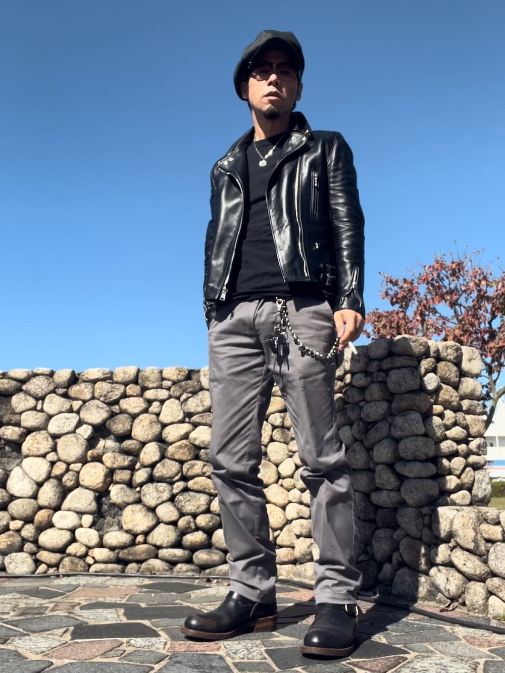 ブラック系のライダースジャケット、ブラック系のTシャツ/カットソー、グレー系のチノパンツを着用したメンズの秋コーディネートの2枚目の写真