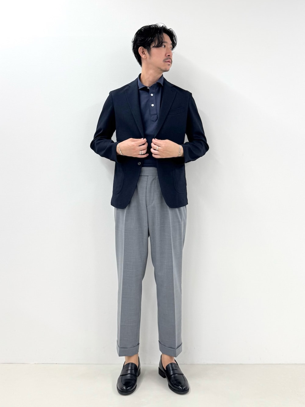 ブルー系のテーラードジャケット、ブルー系のポロシャツ、グレー系のスラックスを着用したメンズの春コーディネートの2枚目の写真