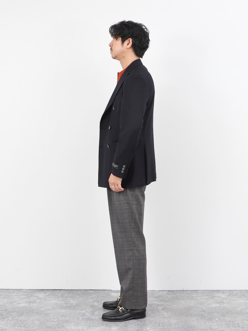 レッド系のニット/セーター、ブルー系のテーラードジャケット、グレー系のスラックスを着用したメンズの秋コーディネートの3枚目の写真