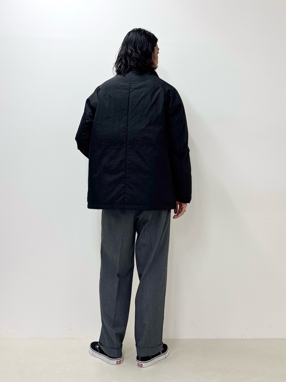 ホワイト系のTシャツ/カットソー、ブラック系のダウンジャケット/コート、グレー系のスラックスを着用したメンズの秋コーディネートの3枚目の写真