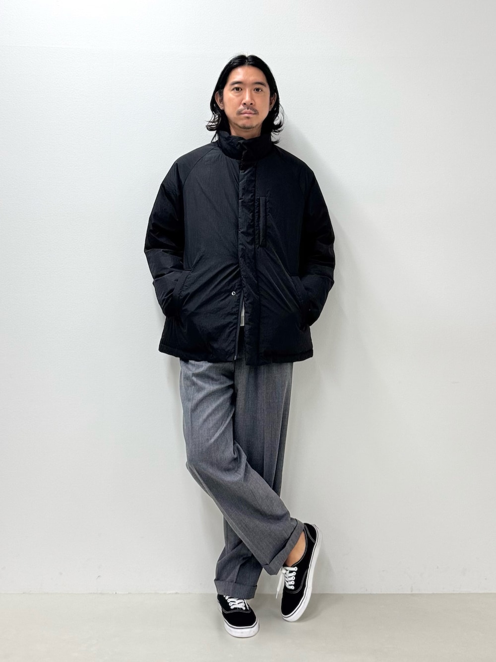 ホワイト系のTシャツ/カットソー、ブラック系のダウンジャケット/コート、グレー系のスラックスを着用したメンズの秋コーディネートの4枚目の写真
