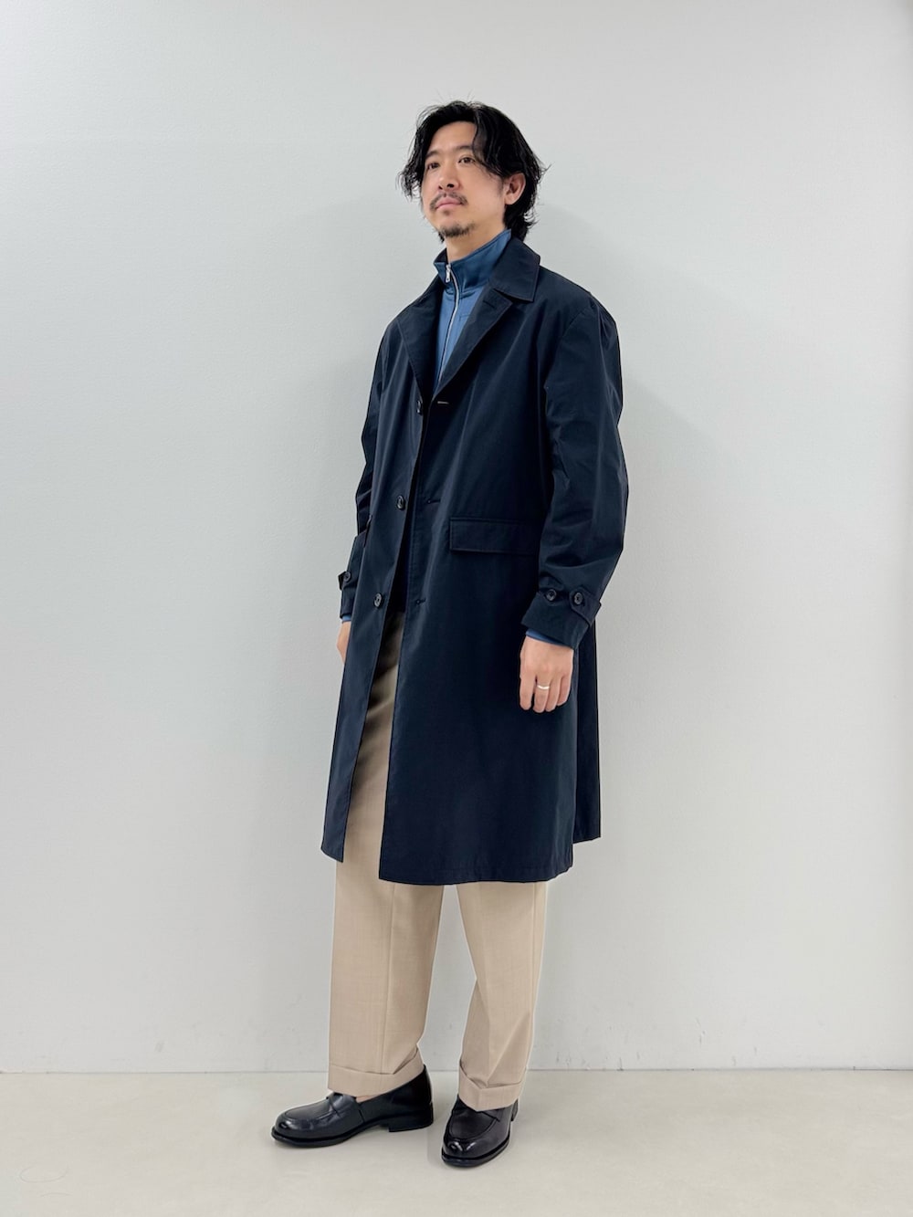 ブルー系のブルゾン、ブルー系のステンカラーコート、ベージュ系のスラックスを着用したメンズの春コーディネートの2枚目の写真