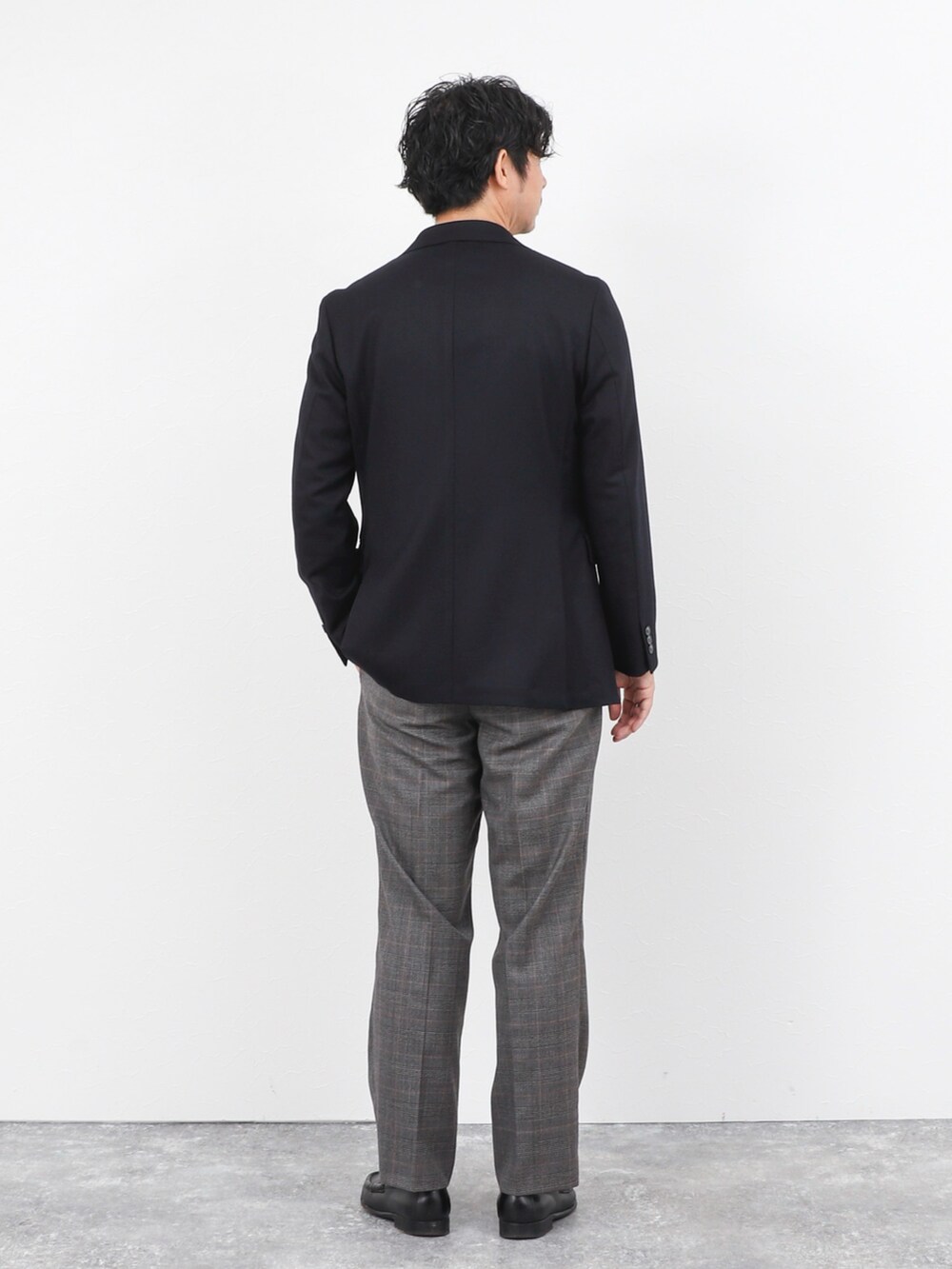 レッド系のニット/セーター、ブルー系のテーラードジャケット、グレー系のスラックスを着用したメンズの秋コーディネートの4枚目の写真