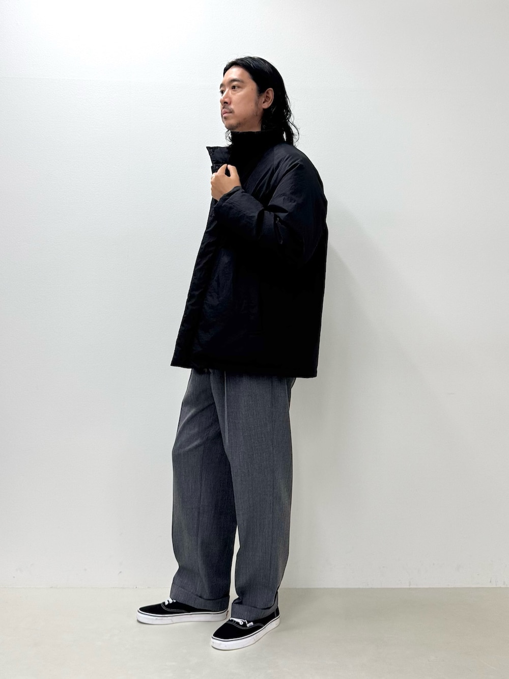 ホワイト系のTシャツ/カットソー、ブラック系のダウンジャケット/コート、グレー系のスラックスを着用したメンズの秋コーディネートの2枚目の写真