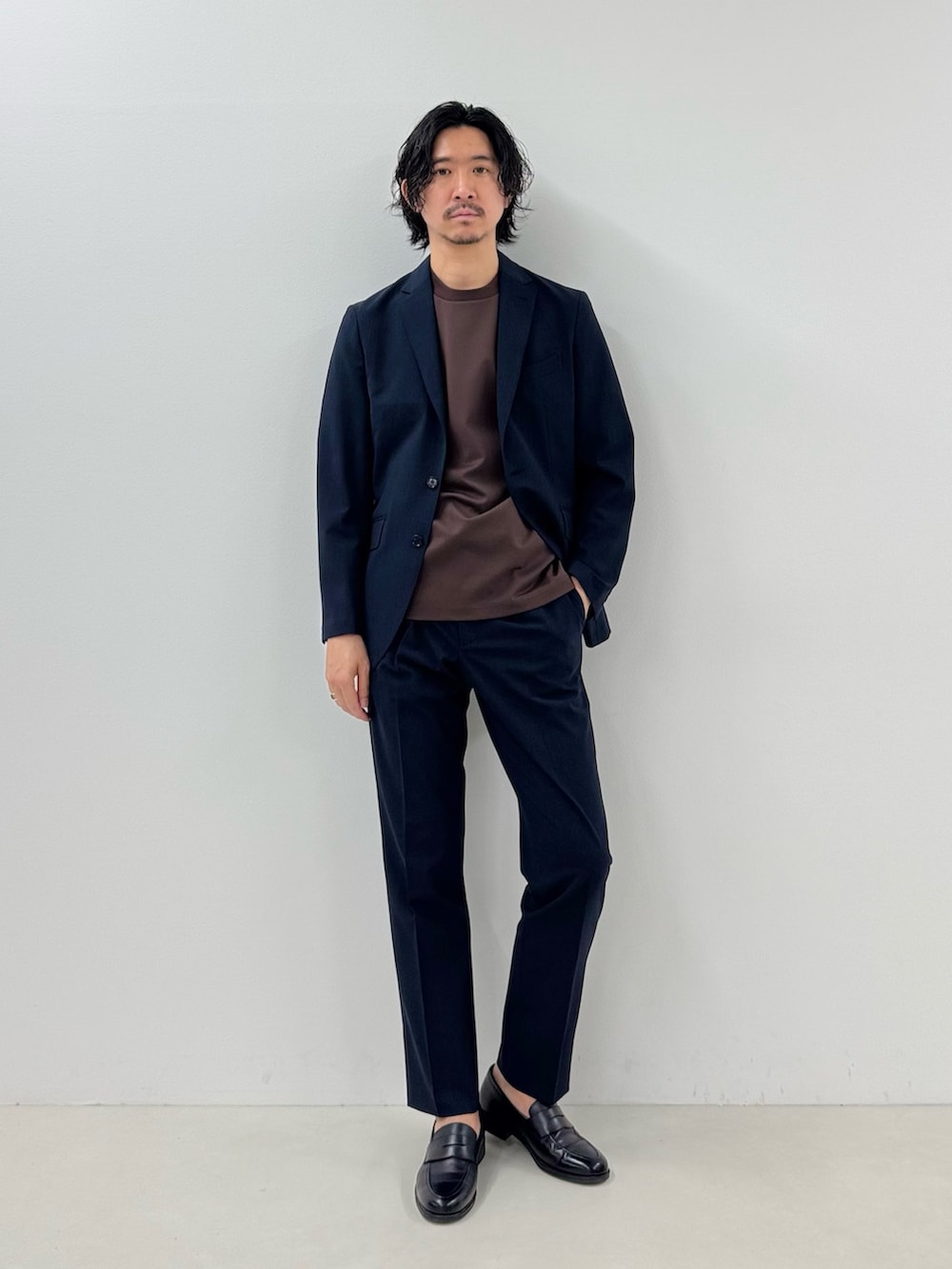 ブルー系のテーラードジャケット、ブラウン系のTシャツ/カットソー、ブルー系のスラックスを着用したメンズの春コーディネートの2枚目の写真