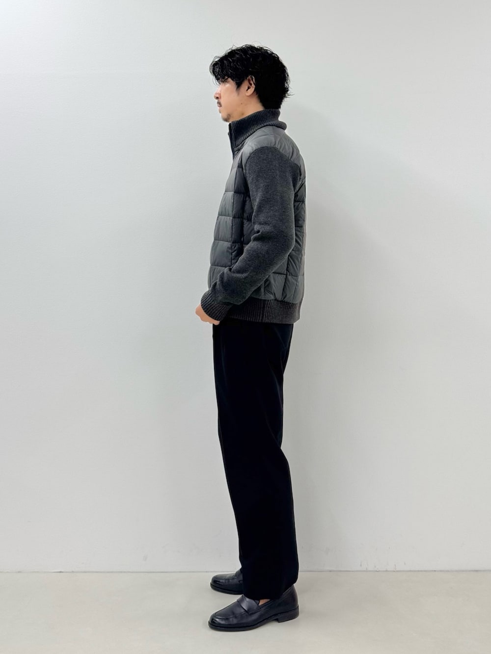 グレー系のブルゾン、イエロー系のTシャツ/カットソー、ブラック系のスラックスを着用したメンズの秋コーディネートの2枚目の写真