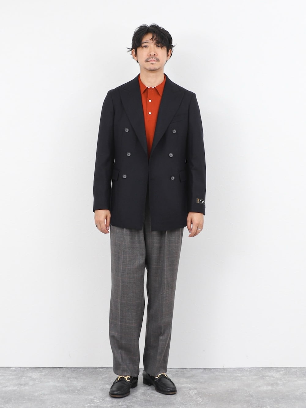 レッド系のニット/セーター、ブルー系のテーラードジャケット、グレー系のスラックスを着用したメンズの秋コーディネートの2枚目の写真