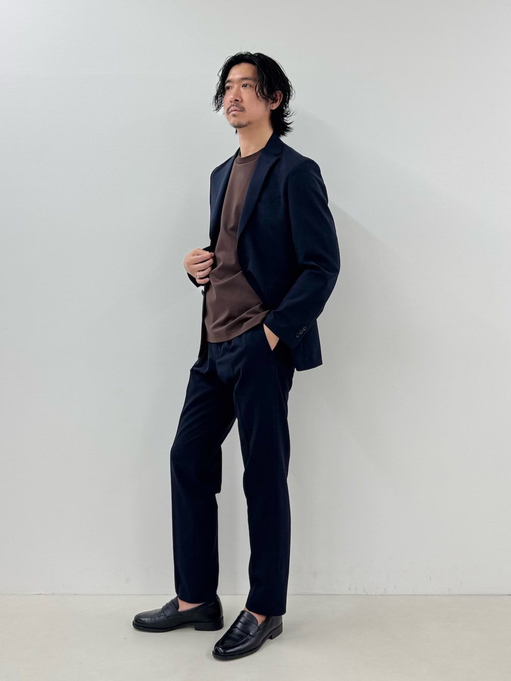 ブルー系のテーラードジャケット、ブラウン系のTシャツ/カットソー、ブルー系のスラックスを着用したメンズの春コーディネートの3枚目の写真