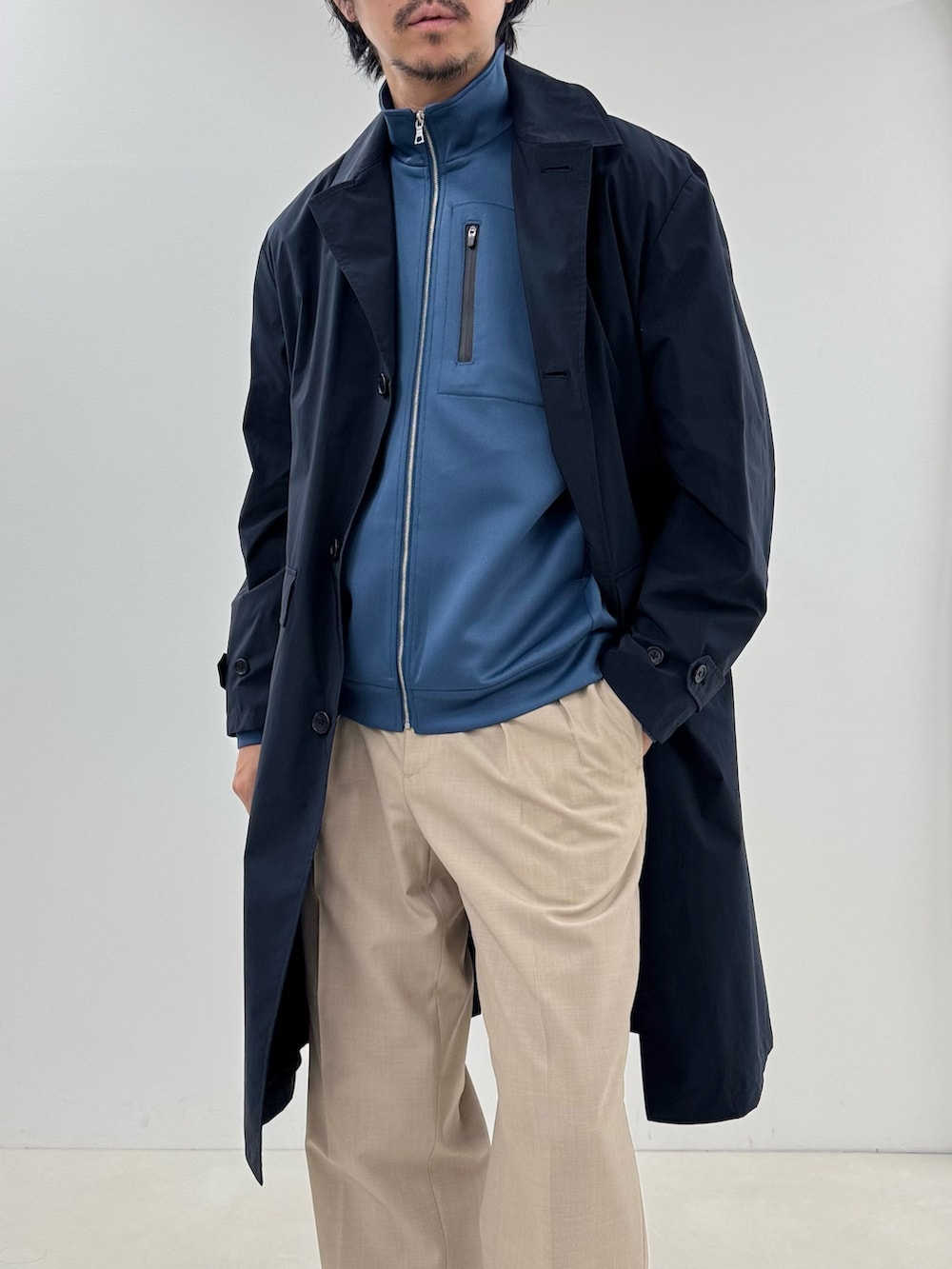 ブルー系のブルゾン、ブルー系のステンカラーコート、ベージュ系のスラックスを着用したメンズの春コーディネートの5枚目の写真