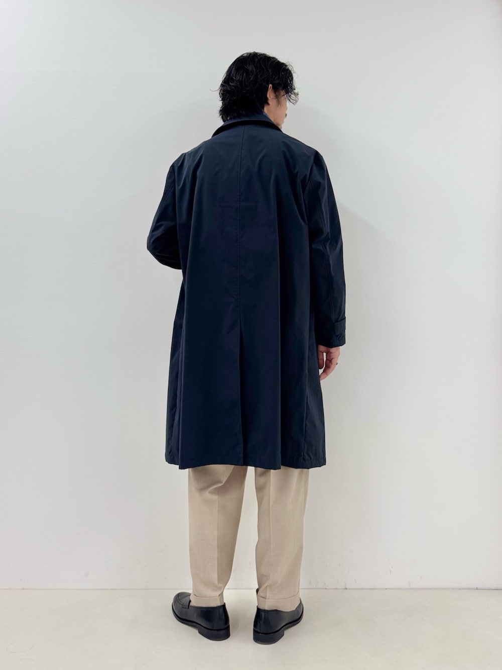 ブルー系のブルゾン、ブルー系のステンカラーコート、ベージュ系のスラックスを着用したメンズの春コーディネートの3枚目の写真