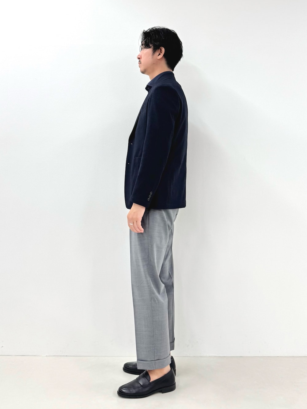 ブルー系のテーラードジャケット、ブルー系のポロシャツ、グレー系のスラックスを着用したメンズの春コーディネートの3枚目の写真