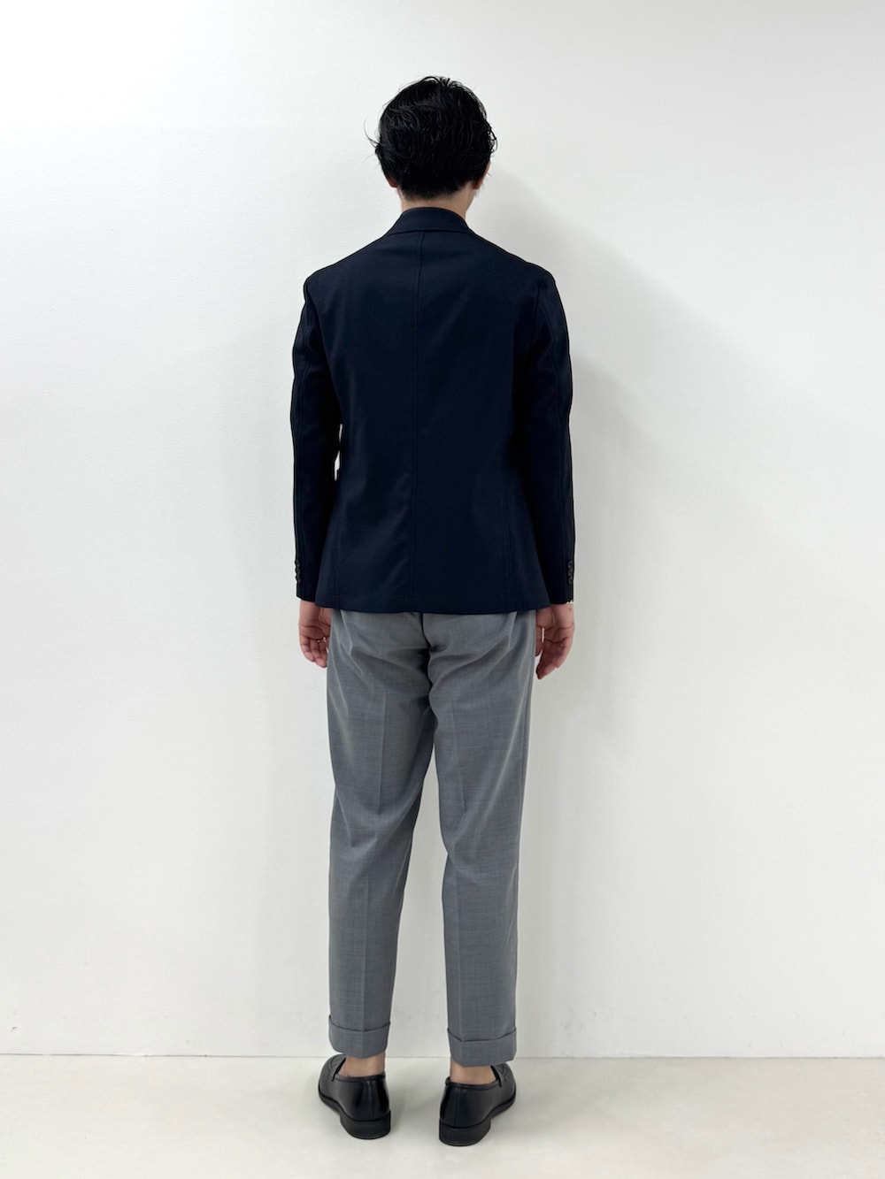 ブルー系のテーラードジャケット、ブルー系のポロシャツ、グレー系のスラックスを着用したメンズの春コーディネートの4枚目の写真