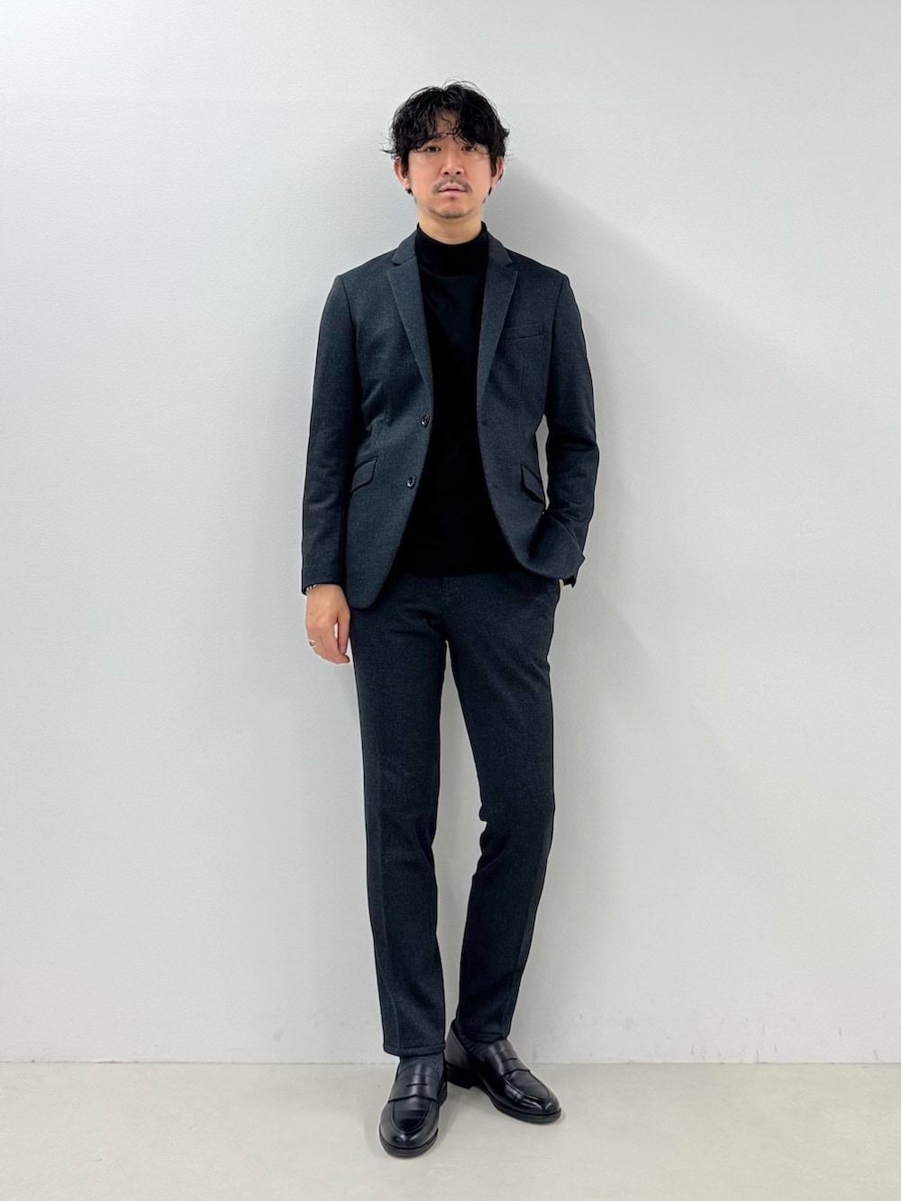 グレー系のテーラードジャケット、ブラック系のTシャツ/カットソー、グレー系のその他パンツを着用したメンズの冬コーディネートの2枚目の写真