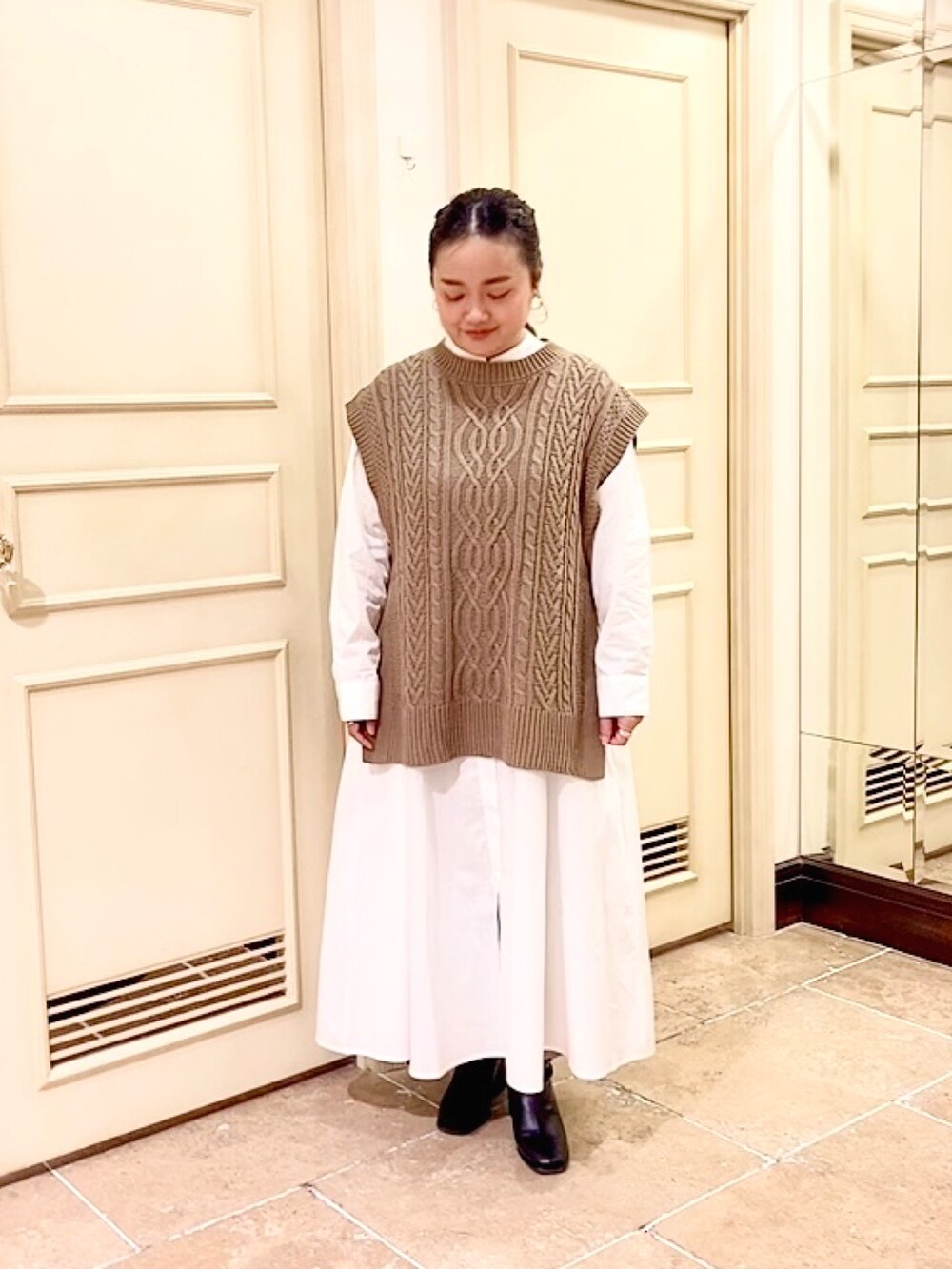 ブラウン系のベスト、ブルー系のデニムパンツ、ホワイト系のシャツワンピースを着用したレディースの秋コーディネートの3枚目の写真