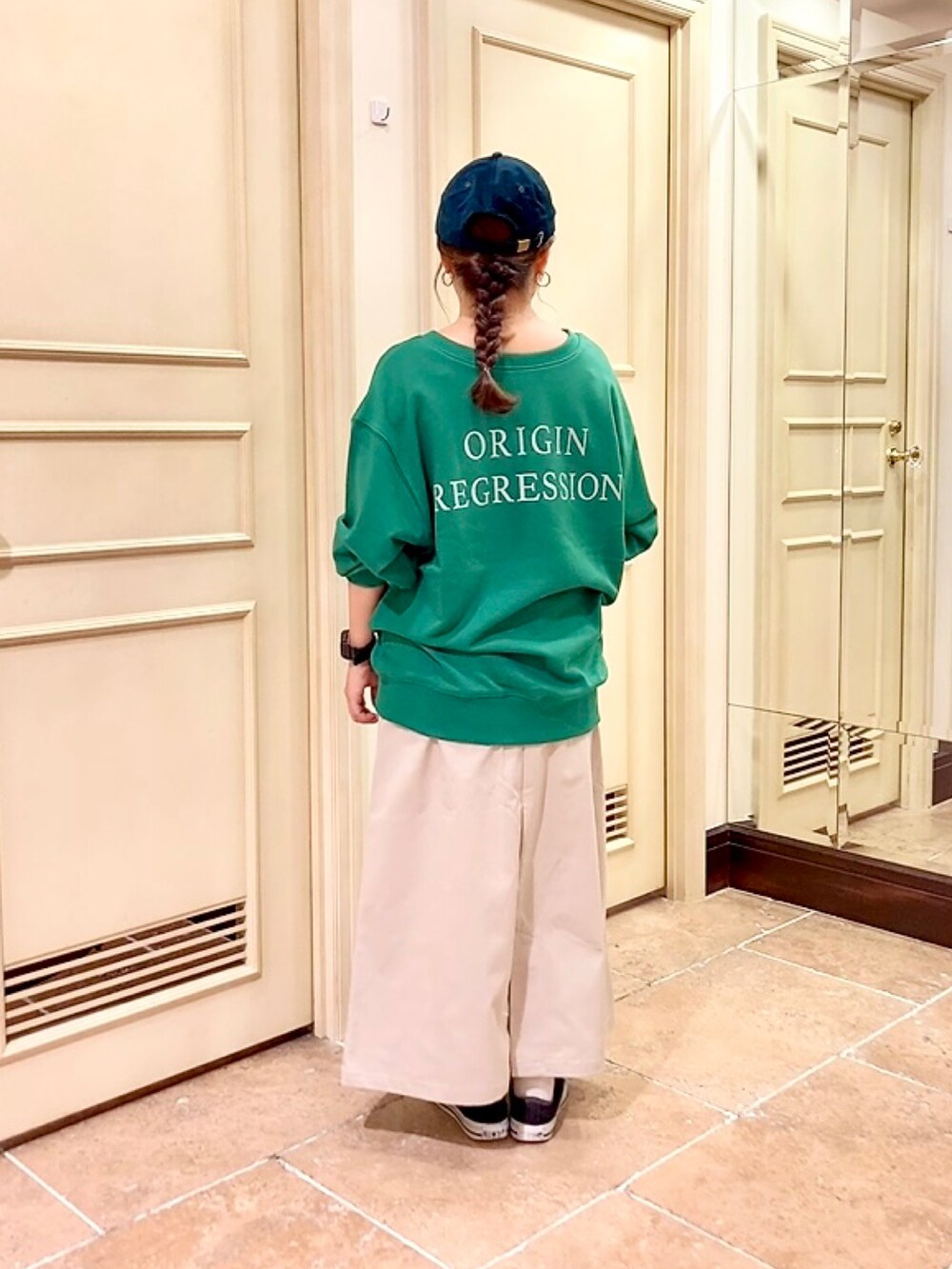 ブラック系のスニーカー、グリーン系のTシャツ/カットソー、ホワイト系のスカートを着用したレディースの秋コーディネートの2枚目の写真